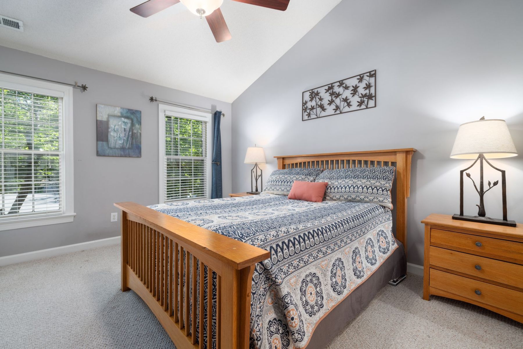 A furnished private bedroom with a bed, wooden dresser and a sunlit window