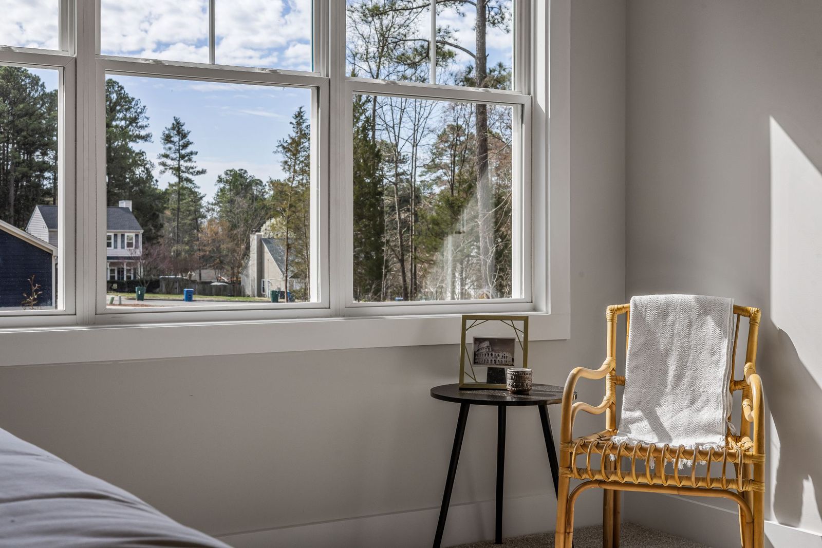 A private bedroom with a made bed, dresser and natural light